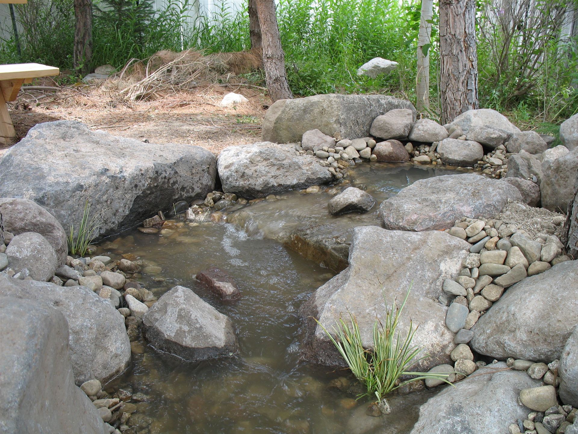 White footbridge over a boulder-lined pond